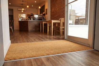 Custom cut coir mat installed flush in a recessed coffee shop entrance