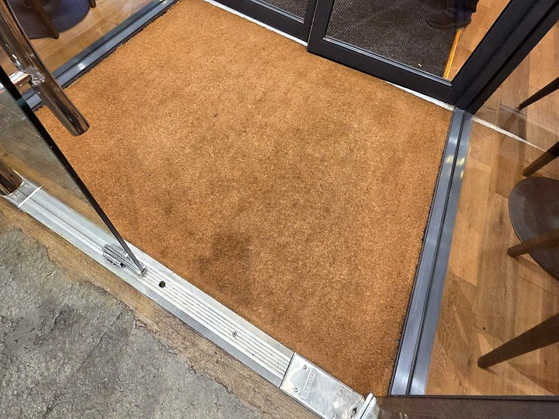 Custom cut natural coir mat installed in a recessed commercial entryway