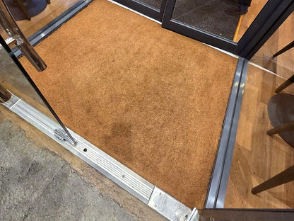 Custom cut natural coir mat installed in a recessed commercial entryway